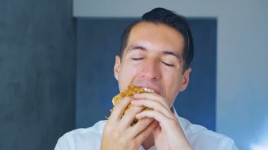 Bir iş adamı Hamburger yiyor. Hızlı yemek. Cheeseburger, hamburger, sandviç.