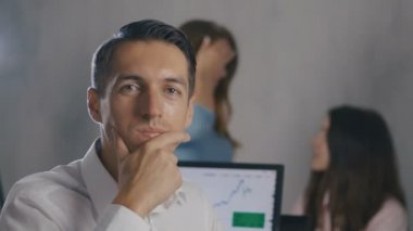 Arka planda insanlar ekibi ile ofiste gülümseyen yüzü ile genç erkek takım lideri Portresi. Profesyonel yönetici işadamı.