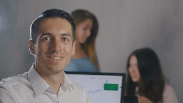 Портрет молодого руководителя команды с улыбающимся лицом в офисе с командой людей на заднем плане. Профессиональный менеджер . — стоковое видео