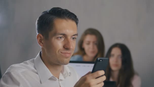 Beyaz gömlekli işadamı, ofis arka planında akıllı telefondan bir mesaj okurken şok ve şaşırttı — Stok video