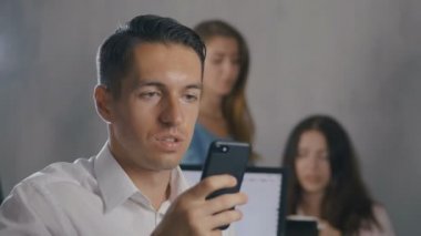Win Tepkisi, Heyecanlı İşadamı tarafından Başarı meslektaşları ile çevrili dizüstü bilgisayar ile ofis masasında otururken akıllı telefon iyi haber almak.