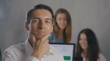 Arka planda insanlar ekibi ile ofiste gülümseyen yüzü ile genç erkek takım lideri Portresi. Profesyonel yönetici işadamı.