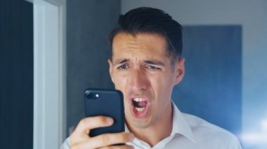 Şok Man bir akıllı telefonda tatsız bir mesaj gördüm. Bir adam bir mesaj akıllı telefonda görüntülendikten sonra facespalm yapar. Hayal kırıklığı, utanç ve utanç kavramı.