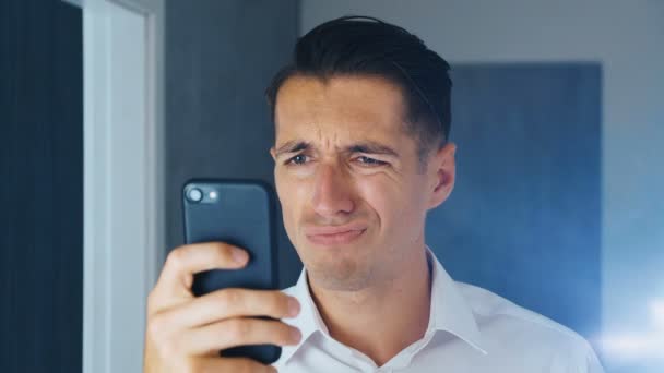 Retrato del hombre conmocionado y disgustado. Un hombre confundido vio un mensaje desagradable en un teléfono inteligente. Está preocupado por ver. Primer plano . — Vídeos de Stock