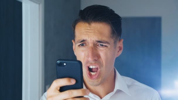 Потрясла людина побачила неприємне послання на смартфоні. Чоловік робить facespalm після перегляду повідомлення на смартфоні. Концепція розчарування, сором і збентеження. — стокове відео