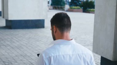 Ofis Binası yakınında yürüyen ve Akıllı Telefonuna Mesaj Yazan Çekici İşadamının Geri Görünümü. İş Yaşam Tarzı.