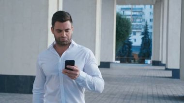 İş Dünyası Sokaklarında Yürüyen ve Cep Telefonu Kullanan İşadamı. Başarılı görünüyor. Beyaz Gömlek giyen sakallı adam. İş Yaşam Tarzı.