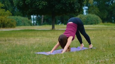 Genç beyaz kadın sabah ları açık hava yerinde yoga yaparak dinlendiriyor. Güzel kadın yeşil çim parkta yoga yapıyor