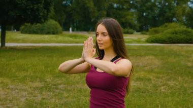 Genç güzel kadın o huzur hissi yaz parkında açık hava eğitimi sırasında meditasyon. Sportif kız sabahları dışarıda yoga yapıyor. Yavaş çekim