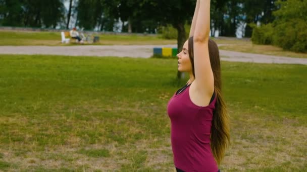 Joven hermosa mujer meditando durante el entrenamiento al aire libre en el parque de verano que se siente la paz. Chica deportiva haciendo yoga al aire libre en la mañana. Movimiento lento — Vídeos de Stock