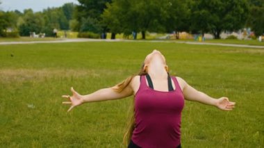 Genç beyaz kadın sabah ları açık hava yerinde yoga yaparak dinlendiriyor. Güzel kadın yeşil çim parkta yoga yapıyor
