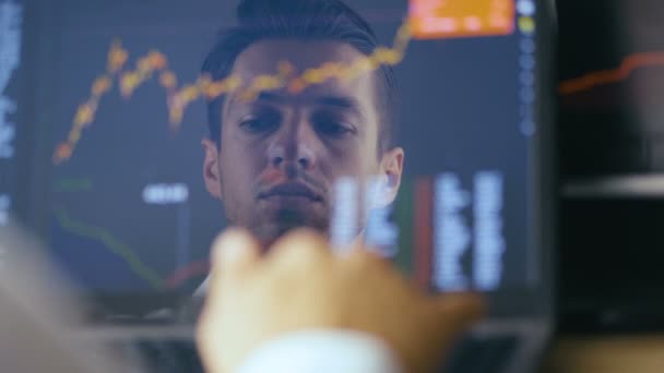 Double exposure: Man Working at Laptop and checks stock market. Reflection in the Monitor: Successful Businessman Working on a Laptop in office and Drinking Tasty Coffee. — Stock Video