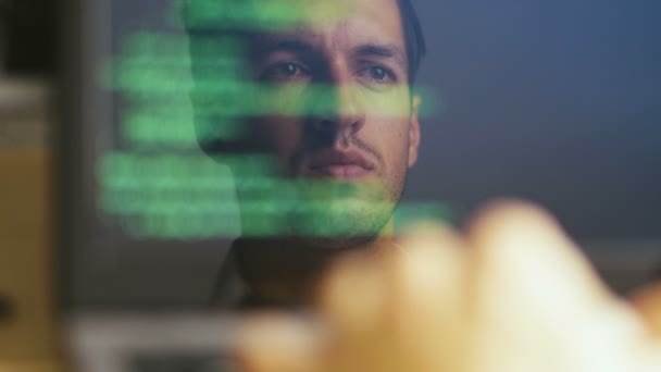 Double Exposure Shot of Man Hacker Programmer trabalhando em um laptop. Reflexão no monitor: Desenvolvedor escreve código verde . — Vídeo de Stock