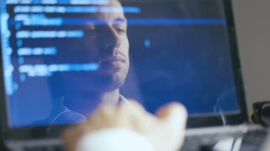Bir dizüstü bilgisayarda çalışan Adam Hacker Programcı Çift Pozlama Shot. Monitörde Yansıma: Geliştirici mavi kod yazar.
