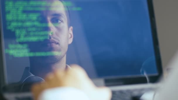 Dubbele belichting shot van man hacker programmeur werken op een laptop. Reflectie in monitor: ontwikkelaar schrijft groene code en koffie drinken. — Stockvideo