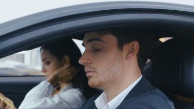 Genç Yakışıklı Adam'ın arabasının direksiyonunda otururken kameraya baka baka yakın çekimi. Arabada oturan kadın ve erkek