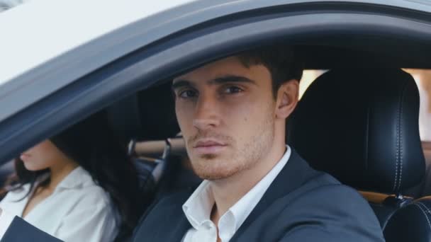 Close-up of Young Handsome Man looking at camera while sitting at wheel of his car. Man and woman sitting in a car — Stock Video