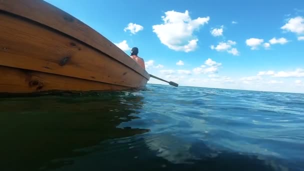 Ο άνθρωπος πλέει σε μια βάρκα κωπηλατεί κουπιά. Κάμερα δίπλα στο νερό. Ταξίδι. — Αρχείο Βίντεο
