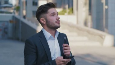 Big Office Binası yakınında Akıllı Telefon ve Sigara Iqos kullanarak Takım Elbise Genç Yakışıklı İşadamı. İş Yaşam Tarzı.