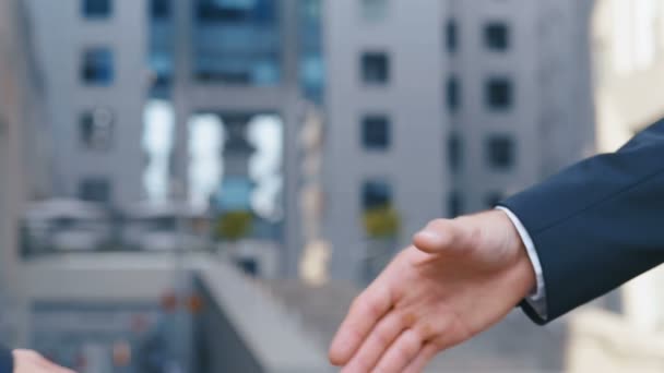 Close-up van de handen van topmanagers in business suits, schud handen met elkaar, op de achtergrond van het Business Center, ga akkoord met een deal of zeg hallo. Slow Motion, onherkenbaar persoon — Stockvideo