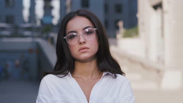 Retrato de una joven empresaria de éxito en gafas de pie cerca de Modern Office Building mirando seriamente a la cámara 4k — Vídeo de stock