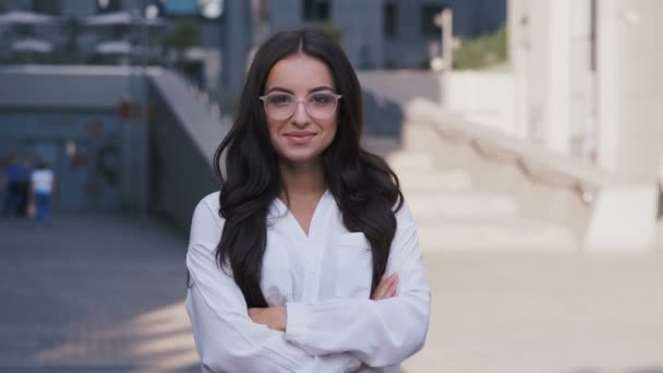 Portret van jonge succesvolle zakenvrouw in brillen staande in de buurt van modern kantoorgebouw kijkend naar camera en glimlachend 4k — Stockvideo