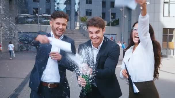 Группа взволнованных деловых людей, празднующих с бутылкой шампанского и тост за свой успех на открытом воздухе в современном бизнес-офис-центр фоне . — стоковое видео