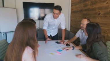 Genç yaratıcı ekibe yön veren erkek takım lideri. Modern ofiste yaratıcı iş toplantısı.