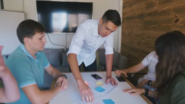 Vijf zakelijke mensen die op de vergadertafel zitten, bespreken energiek de dagelijkse bedrijfsplannen. Mannelijke leider bespreekt werk bij Team Meeting. — Stockvideo