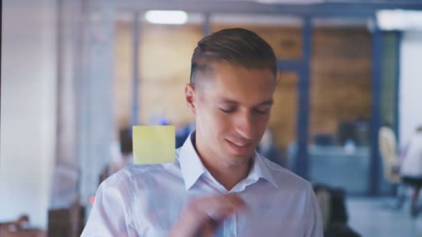 Junger Geschäftsmann zeigt auf klebrige Zettel an einem Glas im Büro, Start-up-Entwicklung und Brainstorming-Konzept — Stockvideo