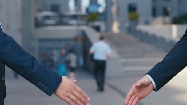 Крупним планом руки топ-менеджерів в ділових костюмах, потисніть руки один одному, на фоні бізнес-центру, погодитися на угоду або привітатися. Повільний рух, невпізнавана людина — стокове відео