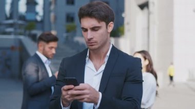 Akıllı Telefon ve arka planda iş tartışırken iş adamları grubu kullanarak meşgul İş Adamı Portresi. Merkez İş Bölgesi'nde çalışıyor. Klasik Takım Elbise Giymek.