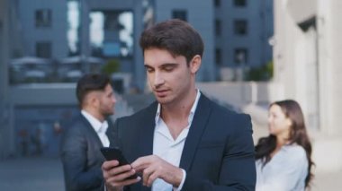 Yakışıklı İşadamı İş Mahallesindeki Akıllı Telefonunda Uygulama Kullanıyor. Haberleri kontrol ediyorum, Mails. Kendinden emin ve başarılı görünüyorsun. Takım Elbiseli.