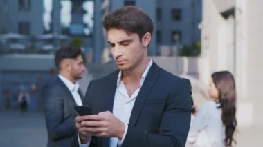 Akıllı Telefon ve arka planda iş tartışırken iş adamları grubu kullanarak meşgul İş Adamı Portresi. Merkez İş Bölgesi'nde çalışıyor. Klasik Takım Elbise Giymek.