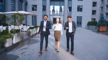 Başarılı İş Adamları İş Tartışmak ve Central Business District yürümek. İki Genç Erkek ve Takım Elbiseli Bir Kadın İletişim ve İş Merkezi Ofis Binası yakınında yürümek.