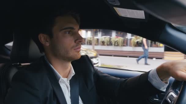 Un hombre de negocios guapo conduciendo un coche. Retrato de un joven confiado conduce un coche en una ciudad . — Vídeo de stock