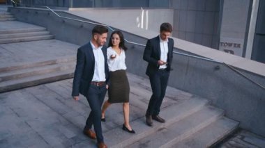 Başarılı İş Adamları İş Tartışmak ve Central Business District yürümek. İki Genç Erkek ve Takım Elbiseli Bir Kadın İletişim ve İş Merkezi Ofis Binası yakınında yürümek.