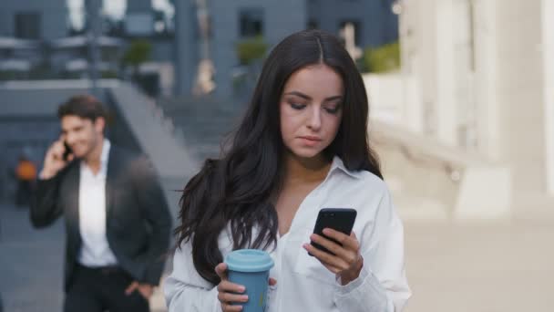 커피 휴식 시간 동안 스마트 폰을 사용하여 성공적인 사업가의 초상화. 아름다운 여성 임원 야외 서 사무실 건물 비즈니스 센터 근처 그녀의 스마트 폰에 SMS를 작성. — 비디오