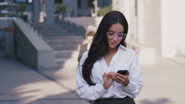 Retrato de una exitosa mujer de negocios con gafas y camisa blanca usando un teléfono inteligente cerca del Office Building Business Center . — Vídeos de Stock