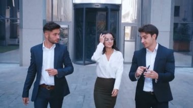 Başarılı İş Adamları İş Tartışmak ve Central Business District yürümek. İki Genç Erkek ve Takım Elbiseli Bir Kadın İletişim ve İş Merkezi Ofis Binası yakınında yürümek.