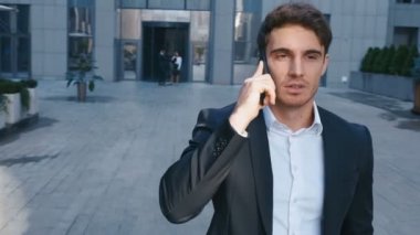 Yakışıklı İş Adamı İş Mahallesi Sokaklarında Cep Telefonuyla Konuşuyor. Ofis iş binası yakınında akıllı telefon kullanan genç kendinden emin adam.