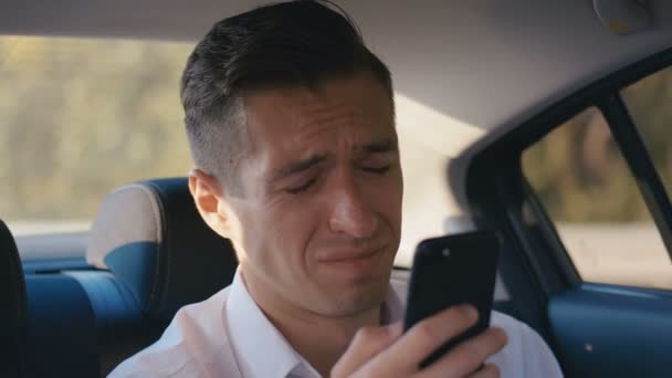 İşadamı, taksiye binerken akıllı telefonunda okuduğu kötü mesajkarşısında şok oldu. Bir Sürücü ile Bir Arabada Seyahat Sırasında Close-Up Shocked ve Stunned adam — Stok video