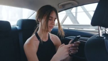 Bir Sürücü ile Bir Arabada Seyahat sırasında Onun Smartphone kullanarak Portre Genç Kadın. Kız o bir Taksi sürmek ise Postalar, Sohbetler kontrol ediyor