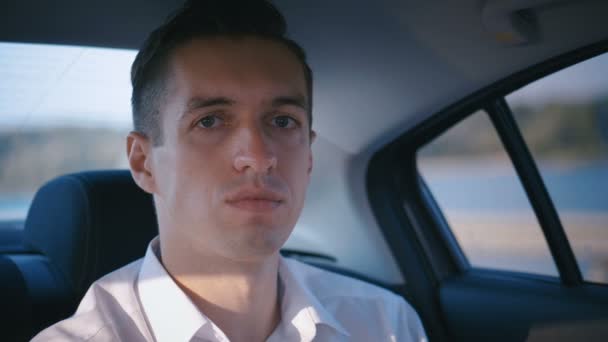 Portrait d'un homme d'affaires voyageant dans une voiture avec chauffeur. Jeune homme en chemise blanche monte dans un taxi — Video