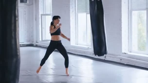 Тхэквондо профессиональная спортсменка бьет боксерскую грушу в спортзале. Спортивный кикбоксинг женщины тренировки в тренажерном зале . — стоковое видео