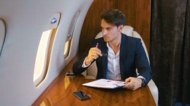 İş adamı özel bir jet uçağında uçarken belgelerle çalışıyor. Business Class.