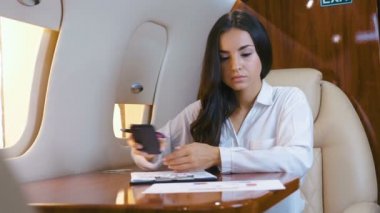 Uçak uçarken kağıt belgelerle çalışan güzel bir iş kadını. İş kadını özel jet uçağıyla seyahat ediyor. Zengin kız birinci sınıfta uçuyor..