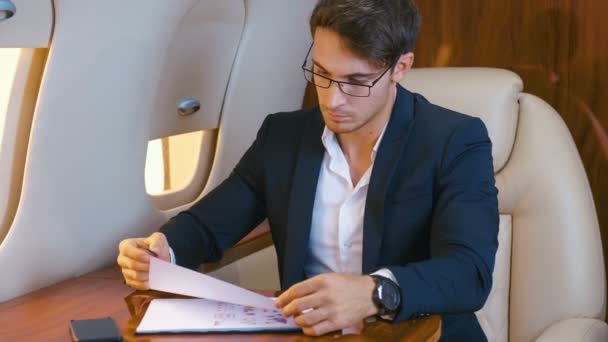 Geschäftsmann arbeitet mit Dokumenten, während er in einem Privatjet fliegt. Business Class. — Stockvideo