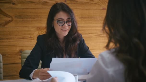 Zwei Geschäftsfrauen sitzen am Konferenztisch und diskutieren einen neuen Businessplan für ein modernes Büro. Teamwork-Konzept. — Stockvideo