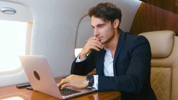 Successful millionere man wearing classical suit using laptop. Traveling in private jet plane. Businessman works at the computer while the plane is flying — Stock Video